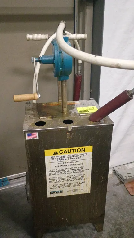 Giles manual oil disposal unit. Features a manual hand-crank rotary pump, flexible hose with wand, transport push handles, and rear wheels.