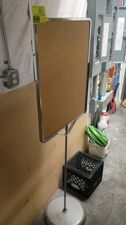 Metal floor-standing sign holder. Features chrome-finish metal frame with rounded corners and backing board. 22" x 65". Mounted on a round weighted ba