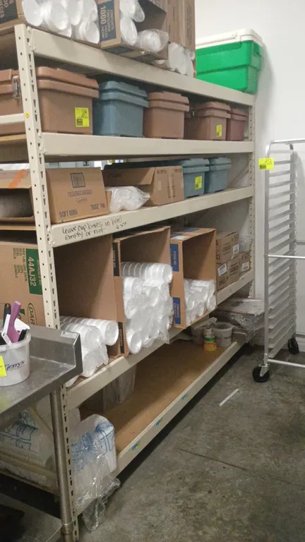 Warehouse storage racking. Features 3" cross beams, wood decking, and beige steel upright frames. Dimensions: 100"W x 50"D x 84"H. Contents not includ