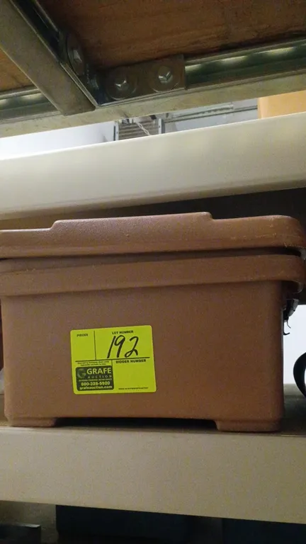 Cambro insulated food transport carrier. Features a top-loading design, brown molded construction, and metal latches. Note: Lower exterior side shows
