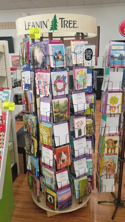 Leanin' Tree rotating greeting card display rack. Features multi-tier wire display pockets, rotating carousel design, and branded top header. 30" x 77