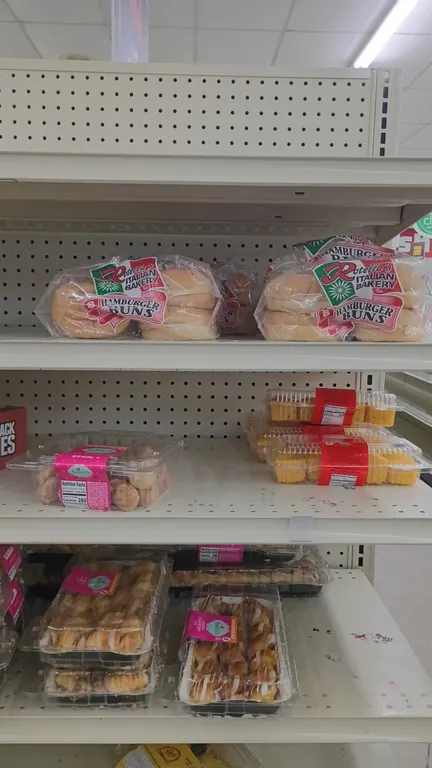 Assorted packaged bakery goods. Includes snack pies, hamburger buns, slider rolls, cinnamon rolls, bagels, pastries, and French bread. Note: Shelving
