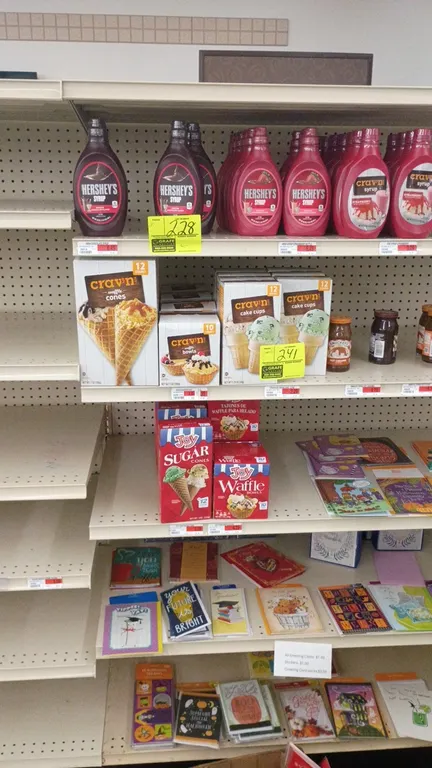 Contents of 4' section. Includes assorted ice cream cones and waffle bowls (Crav'n, Joy), Smucker's toppings, syrups, Skittles freezer pops, and assor