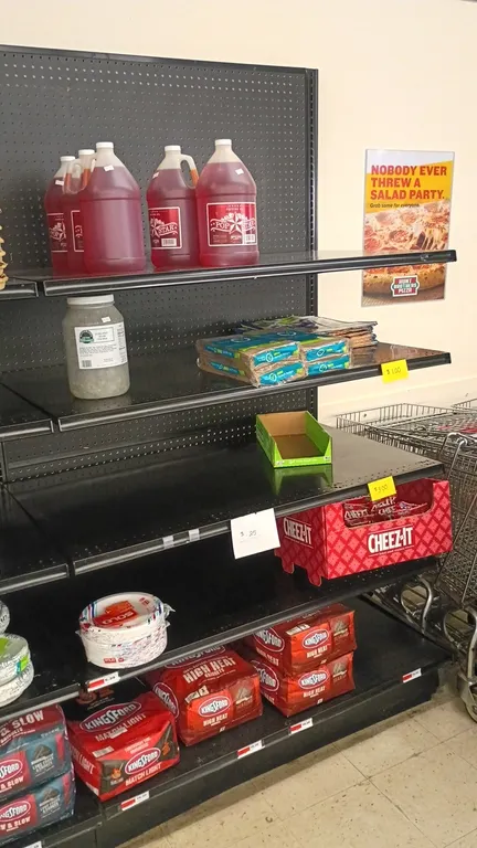 Contents of 8' shelving section. Includes Kingsford charcoal, disposable paper plates and bowls, Mrs. Wages pickling mix packets, Igloo Recool reusabl