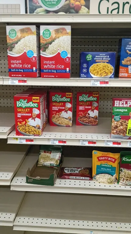 Assorted dry grocery food package lot. Includes contents of 4' shelf section featuring macaroni and cheese, rice pouches and boxes, Chef Boyardee skil
