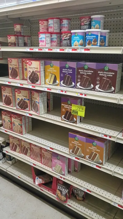 Assorted baking mix and frosting inventory from a 4' shelving section. Includes assorted Betty Crocker and Food Club cake mixes, Betty Crocker and Foo