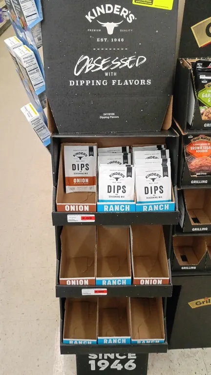 Kinder's cardboard retail floor display stand. Features 3 tiered shelves with product display trays and branded header graphic. Includes assorted Kind