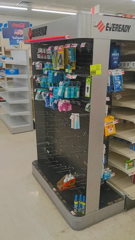Eveready retail pegboard display rack. Features black pegboard backing, side pegboard panels, assorted metal peg hooks, overhead canopy signage, and a