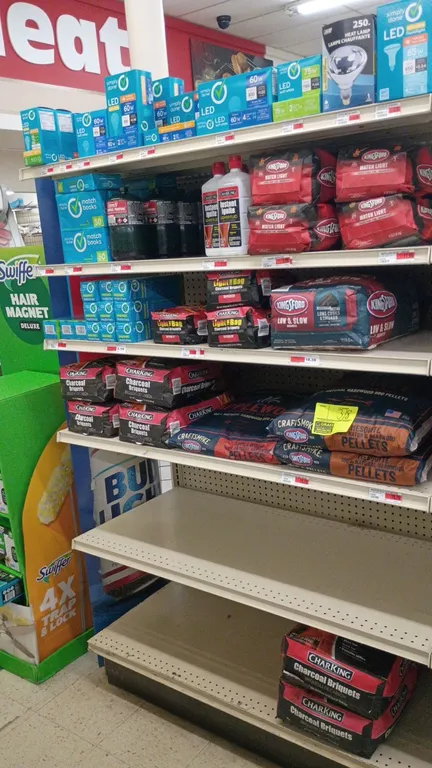 Contents of 4' shelving section. Includes assorted charcoal briquets and BBQ pellets (Kingsford, CharKing), lighter fluid, Coleman propane cylinders,