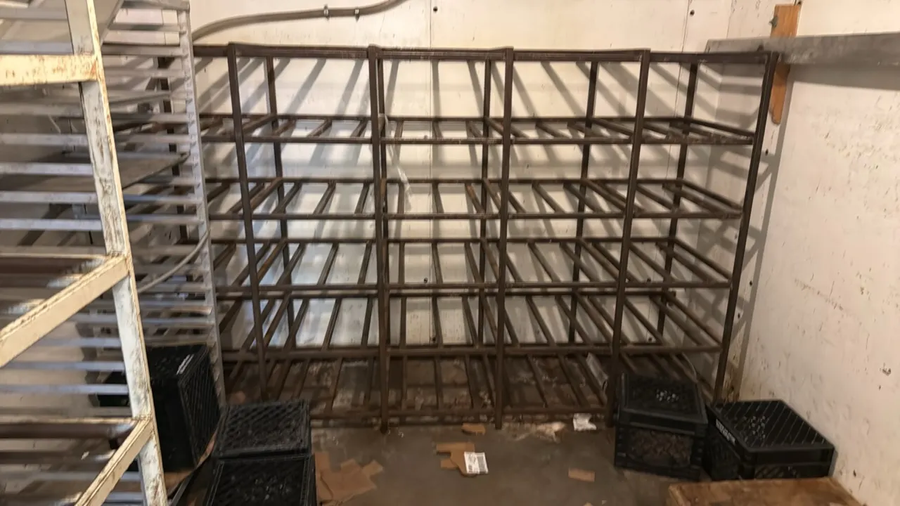 Welded metal storage rack. Features multi-tier tubular frame construction with 5 shelf tiers across 4 section bays. 100" x 64". Surrounding equipment,