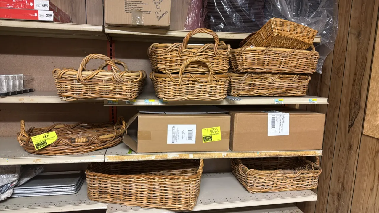 Assorted wicker and wooden display baskets. Features various sizes and styles including handled baskets, woven trays, rectangular baskets, and stacked