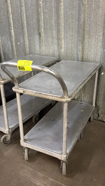 Aluminum 2-tier utility cart. Features tubular push handle and solid metal shelves. 42"L. Mounted on 6 casters.