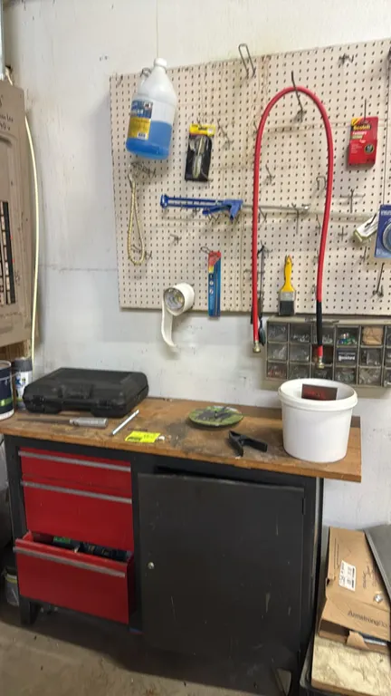 Metal workbench with wood top. Features 3 drawers and a single-door storage cabinet. Includes wall-mount pegboard, multi-drawer small parts organizer,
