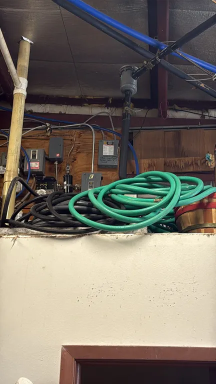 Assorted water hoses. Includes (1) green garden hose and (1) black hose with brass fittings. Background equipment and structures not included.