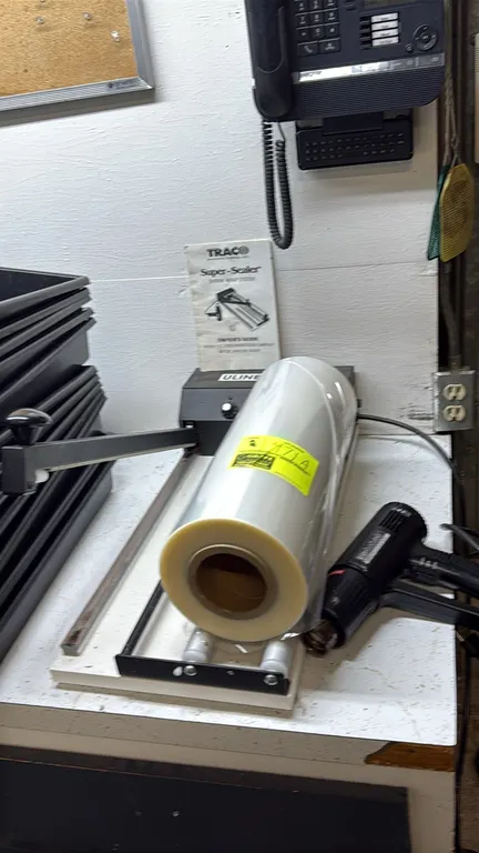 Uline Super-Sealer shrink wrap system. Features impulse seal bar and film roll dispenser with film roll. Includes Hotshot dual-temperature heat gun an