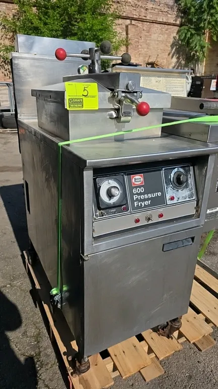 1997 Henny Penny 600 natural gas commercial pressure fryer. Features dial timer, analog temperature control, locking lid assembly, fry basket, and fil
