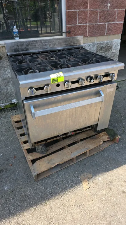 Imperial 6-burner gas range. Features stainless steel exterior, 6 open burners with cast iron grates, back riser, and lower oven base with interior ra