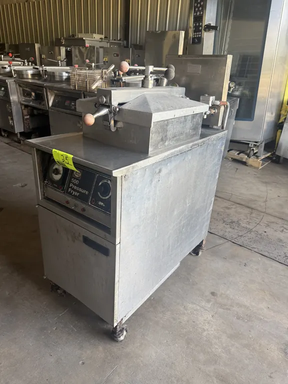 Henny Penny 500 electric pressure fryer. Features stainless steel construction, locking lid assembly, and front dial controls. S/N: LB004IG. Electrica