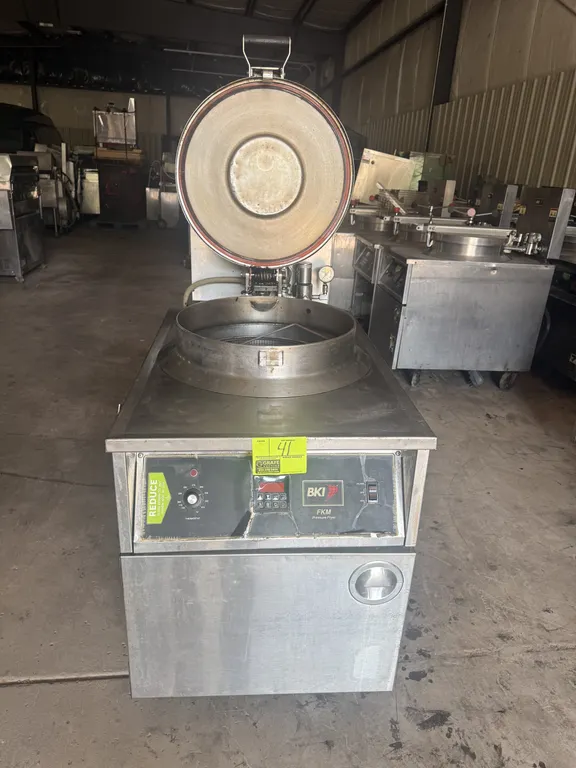 2005 BKI FKM-F electric pressure fryer. Features stainless steel construction, round fry pot with wire basket, locking lid assembly, pressure gauge, a