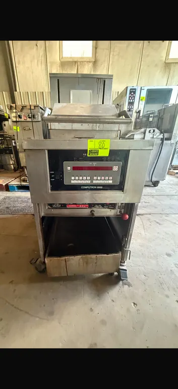 Henny Penny Computron 8000 commercial fryer. Features stainless steel construction, fry vat with wire mesh basket, and metal lid.