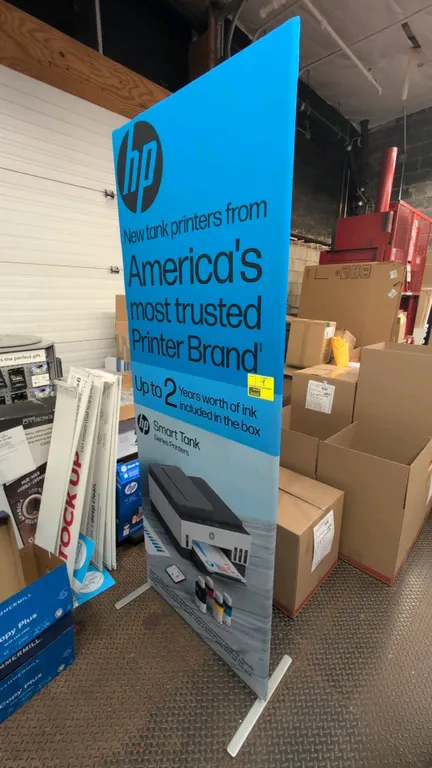 Free-standing retail sign stand. Features HP Smart Tank Series Printers graphic banner. 90"H. Mounted on metal support feet.