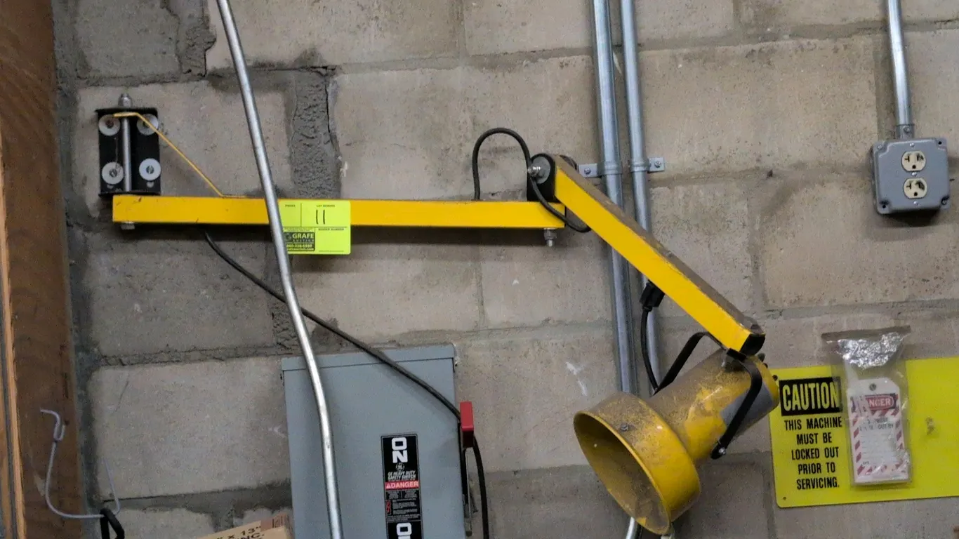Metal adjustable shop light. Features articulated dual-arm extension, yellow metal construction, adjustable lamp fixture, and wall-mounting bracket.