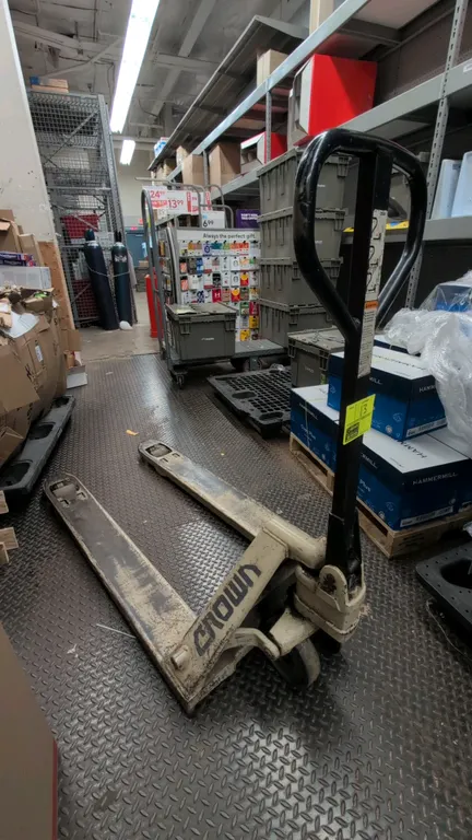 Crown manual pallet jack. Features manual hydraulic lift operation, loop handle with fingertip release control, and steel forks with entry rollers.