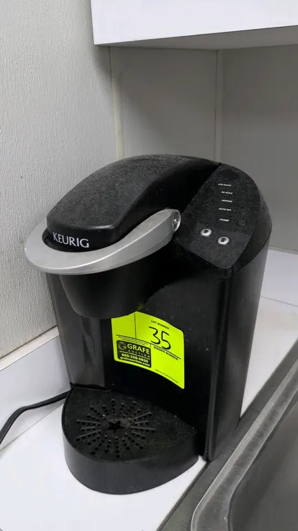 Keurig single-serve coffee maker. Features K-Cup pod brewing chamber, side water reservoir, push-button brew size selection, and removable drip tray.