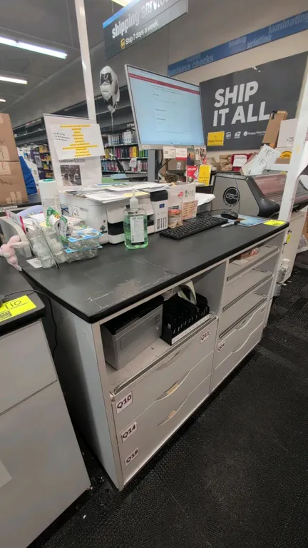 Laminate countertop service counter cabinet. Features a black laminate work surface and integrated lower storage with pull-out trays and drawers. 48"L