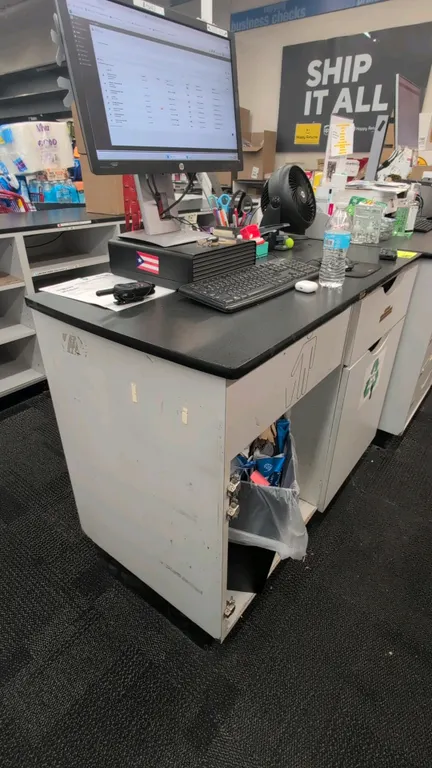 Laminate countertop service cabinet with under-counter storage. Features a black laminate top, integrated waste receptacle opening, and pull-out stora