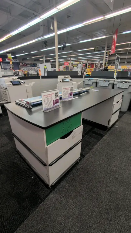 Laminate countertop work table. Features a black laminate top and dual pedestal bases with (2) undercounter waste bin slots and integrated bumper guar