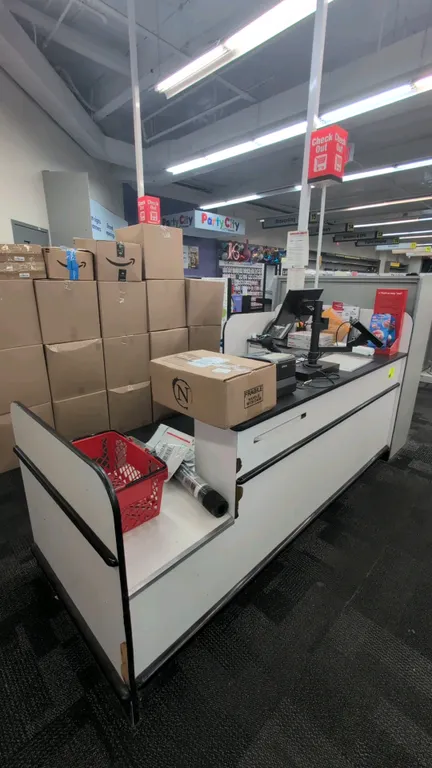 Laminate retail checkout lane counter. Features overhead illuminated 'Check Out' light pole, black countertop, under-counter storage shelving, and low