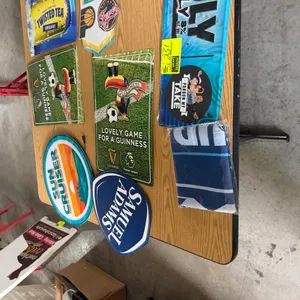 Assorted bar and advertising signage decor. Includes metal tin tackers, branded beverage signs (Samuel Adams, Guinness, Twisted Tea, Sun Cruiser, Trul