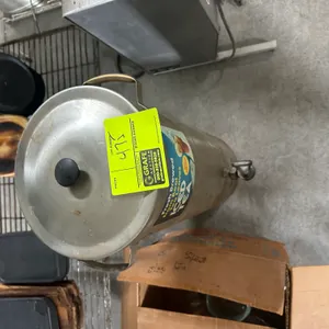 Stainless steel iced tea dispenser. Features stainless steel cylindrical construction, removable top lid, front dispensing spigot, and dual side carry