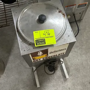 Hot chocolate dispenser. Features stainless steel construction, round top lid with knob handle, graphic front decal, and attached power cord. Mounted 