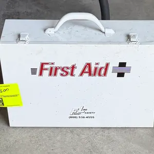 Front Line Safety first aid kit with contents. Features a white metal case with dual latches, top carrying handle, interior shelf, and wall-mounting h