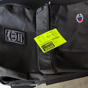 Champion backpack. Features black fabric construction with a Jack Daniel's Old No. 7 Tennessee Whiskey patch, embroidered Champion logo, zippered fron