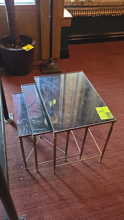 Glass-top metal frame nesting tables. Features glass inset tops, bronze-tone metal frames, fluted legs, and side stretchers. 22" x 18"H.