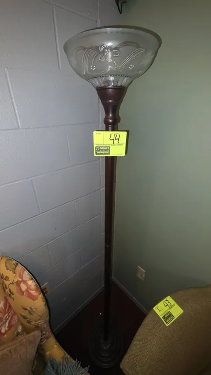 Torchiere floor lamp. Features frosted glass shade with raised floral motif and fluted metal pole. 6'H. Mounted on a circular tiered decorative metal