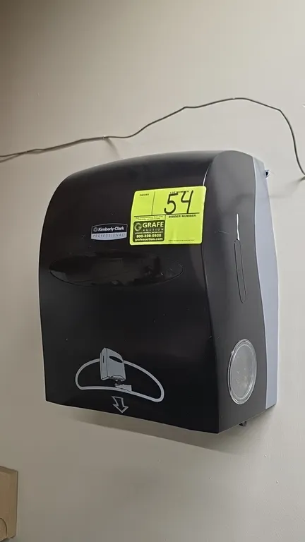 Kimberly-Clark automatic paper towel dispenser. Features black plastic construction, front viewing window, and touchless dispensing. Wall-mounted desi