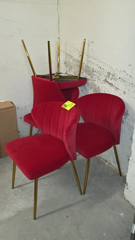 Velvet cushioned accent chairs. Features red velvet upholstery, vertical channel-tufted curved backrests, and padded seats. Mounted on gold-tone taper