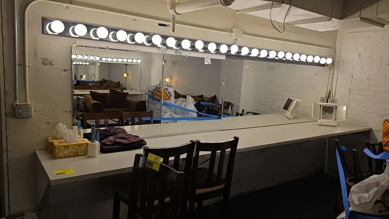 Laminate dressing vanity counter. Includes (2) 2.5' and (1) 7' wall mirrors, and (3) 4' 8-socket vanity light strips. 13' x 2'. Wall-mounted on metal