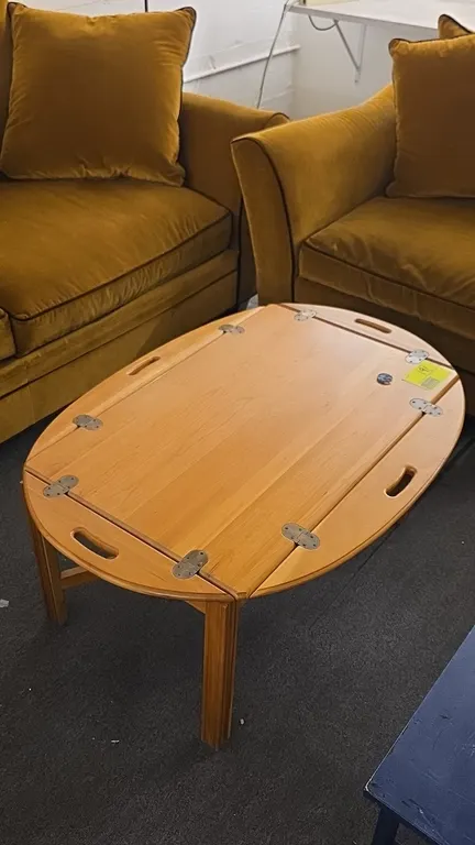 Wood coffee table with folding sides. Features four hinged drop-leaf sides with integrated cutout handles and brass-tone hinges. 42"L. Supported by st