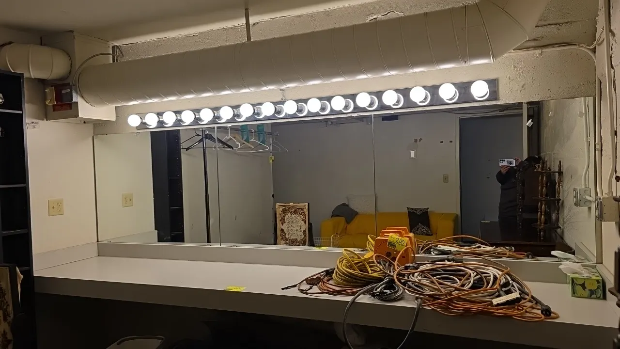 Laminate dressing vanity counter. Includes (3) 4' x 3' wall mirrors and (2) 4' 8-socket vanity light bars. Vanity measures 11'L x 2'W. Contents not in