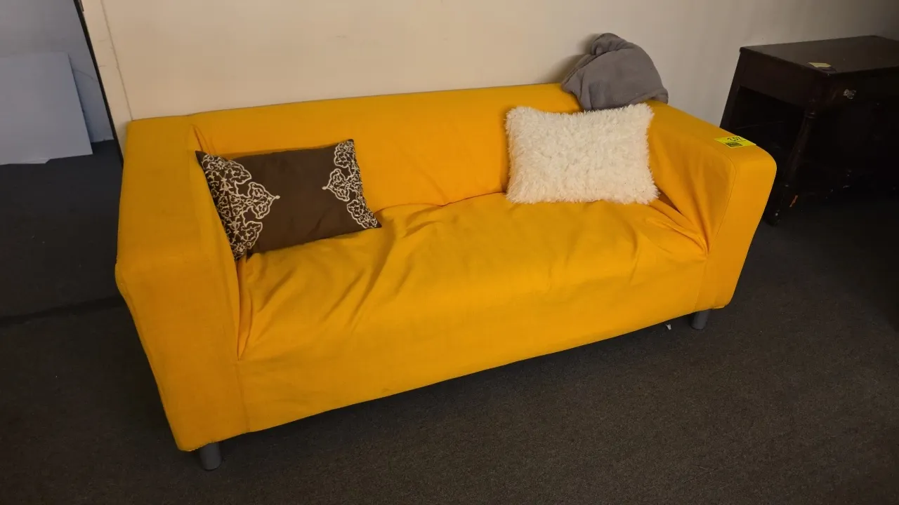 IKEA sofa. Features a yellow fabric slipcover. Includes (2) decorative throw pillows and a throw blanket. 72"L.