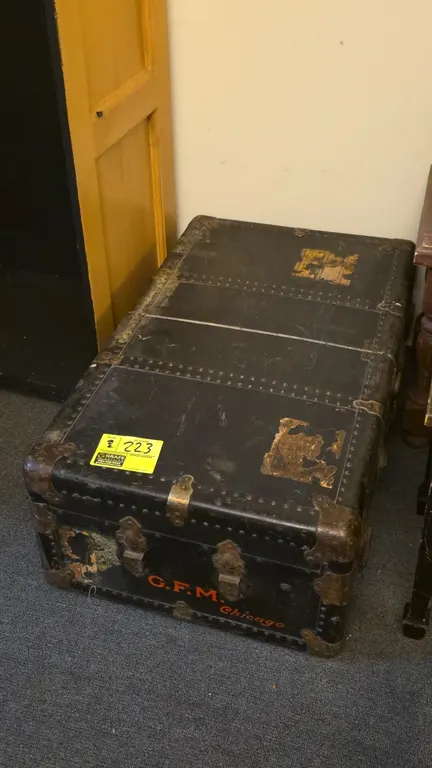 Vintage G.F.M. Chicago travel trunk. Features metal hardware, reinforced corners, studded trim, latches, and vintage travel labels including Canadian