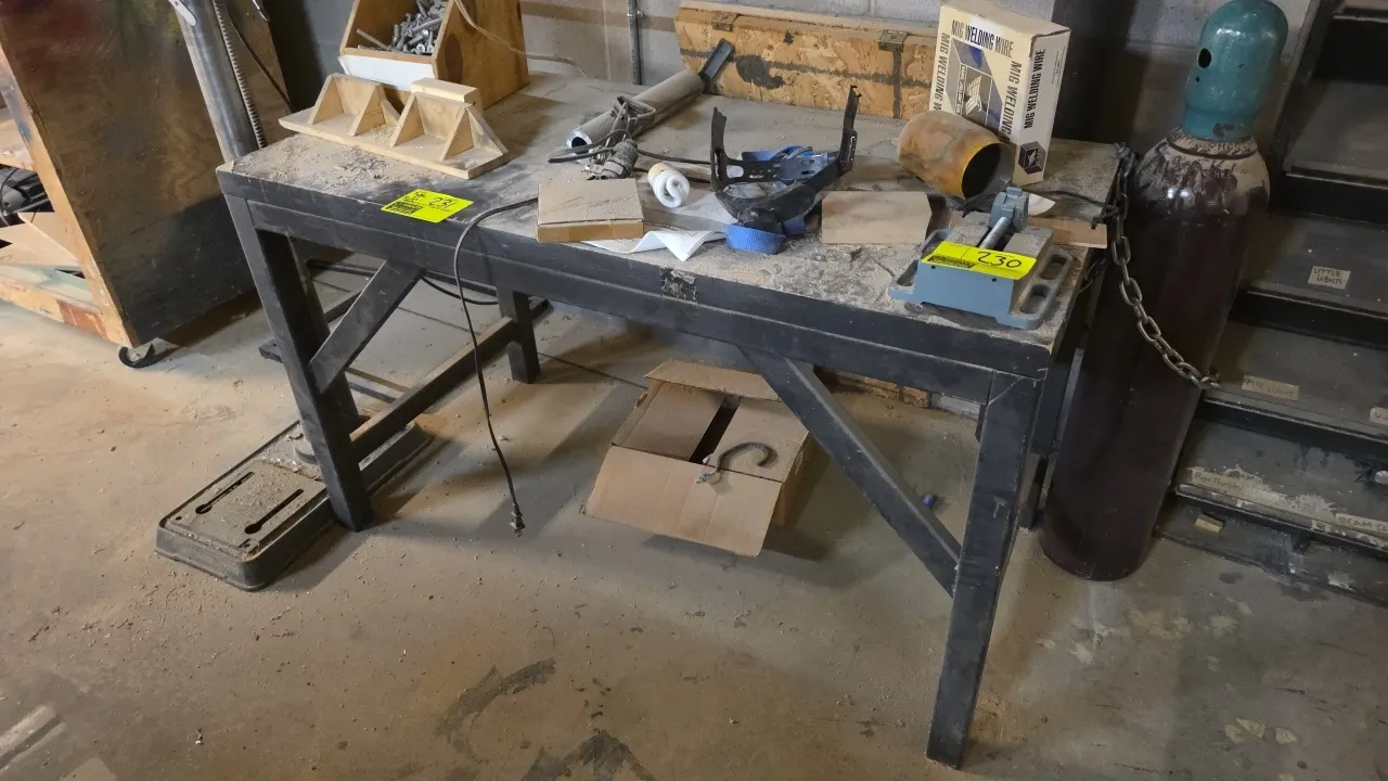 Wood top workbench. Features black steel frame with angled leg bracing. Includes assorted remaining contents including hardware bin, wooden jigs, MIG