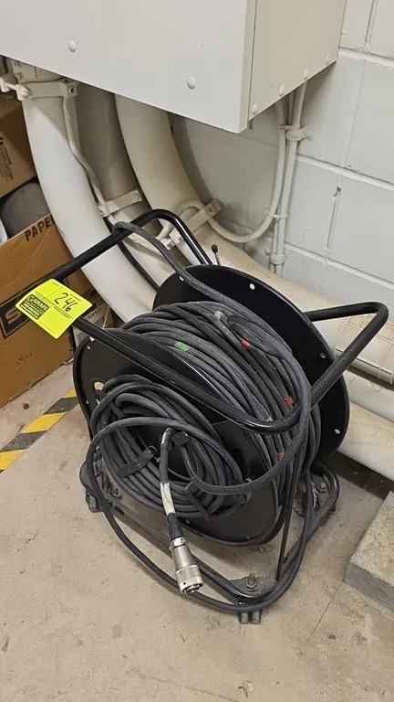 Portable cable reel cart with heavy-duty cable. Features a metal reel drum, tubular steel frame, side cable wrap brackets, and multi-pin circular conn