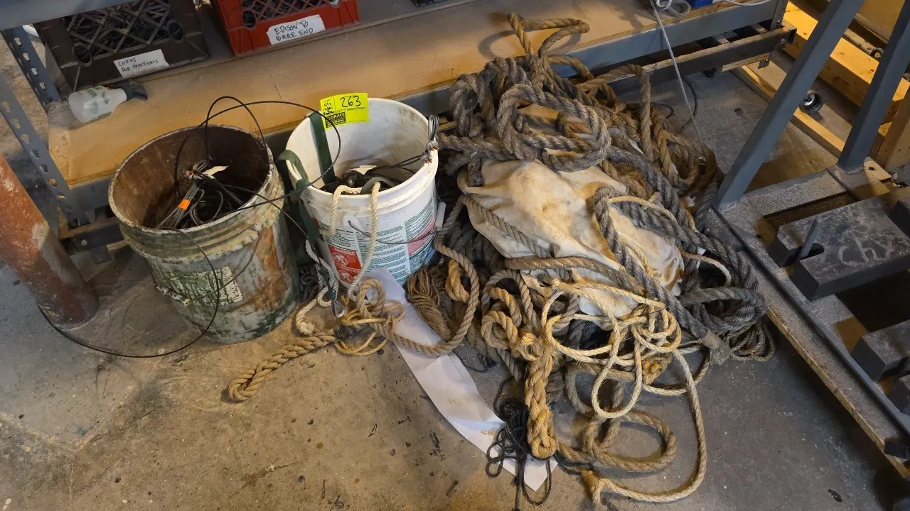 Assorted lot of wire rope cables and heavy fiber ropes. Includes (2) 5-gallon poly buckets containing steel cable assemblies with thimbles and clamps,