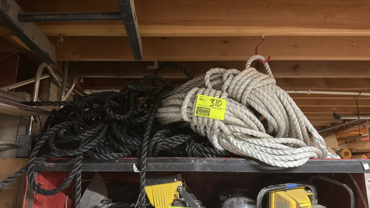 Assorted rope lot. Includes coiled white synthetic rope with tracer and bundled black twisted rope. Cabinet and surrounding contents not included.